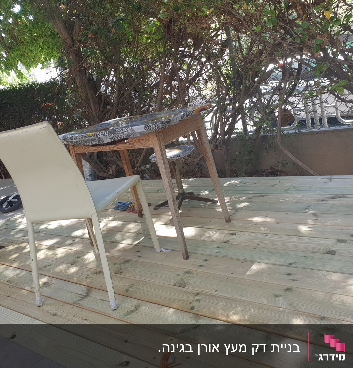 דק עץ עם שולחן וכיסא בגינה